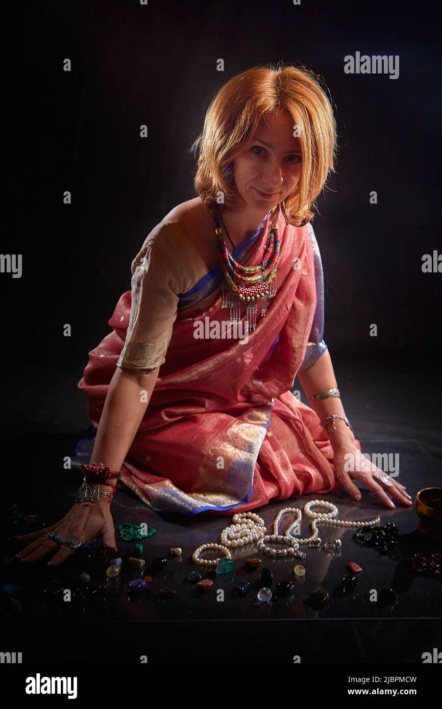 A beautiful European woman in a traditional Indian sari on a black background. Girl model posing in the studio Stock Photo
