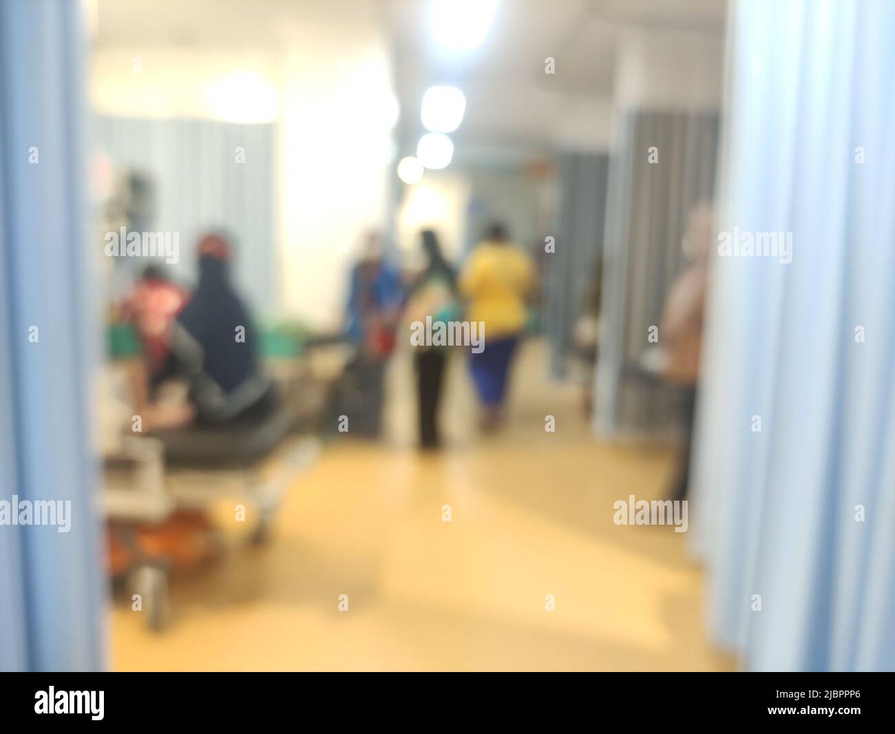 blurred background : atmosphere in the emergency room at the hospital.  the patient is being examined by a doctor and accompanied by his family Stock Photo