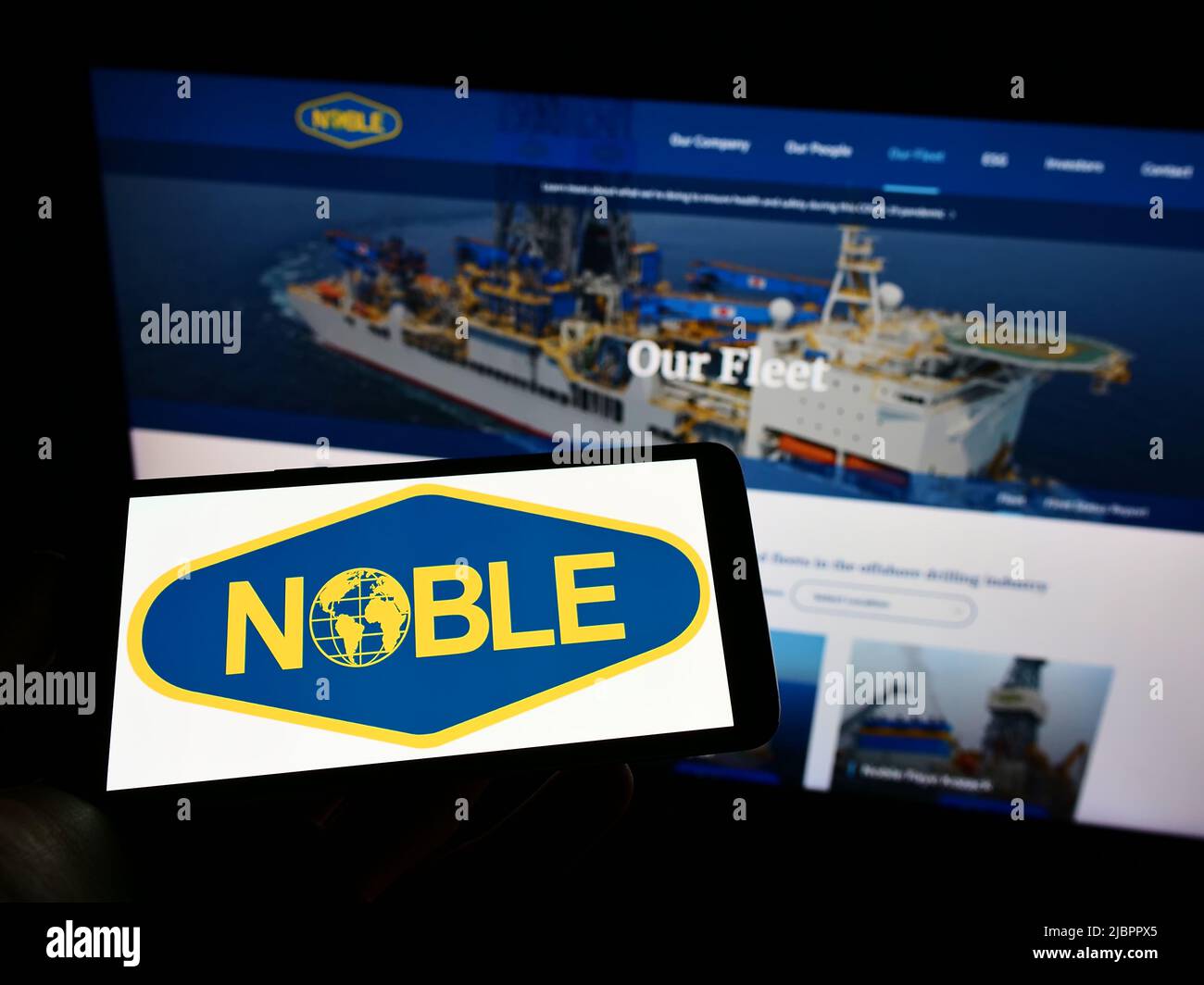 Person holding cellphone with logo of drilling company Noble