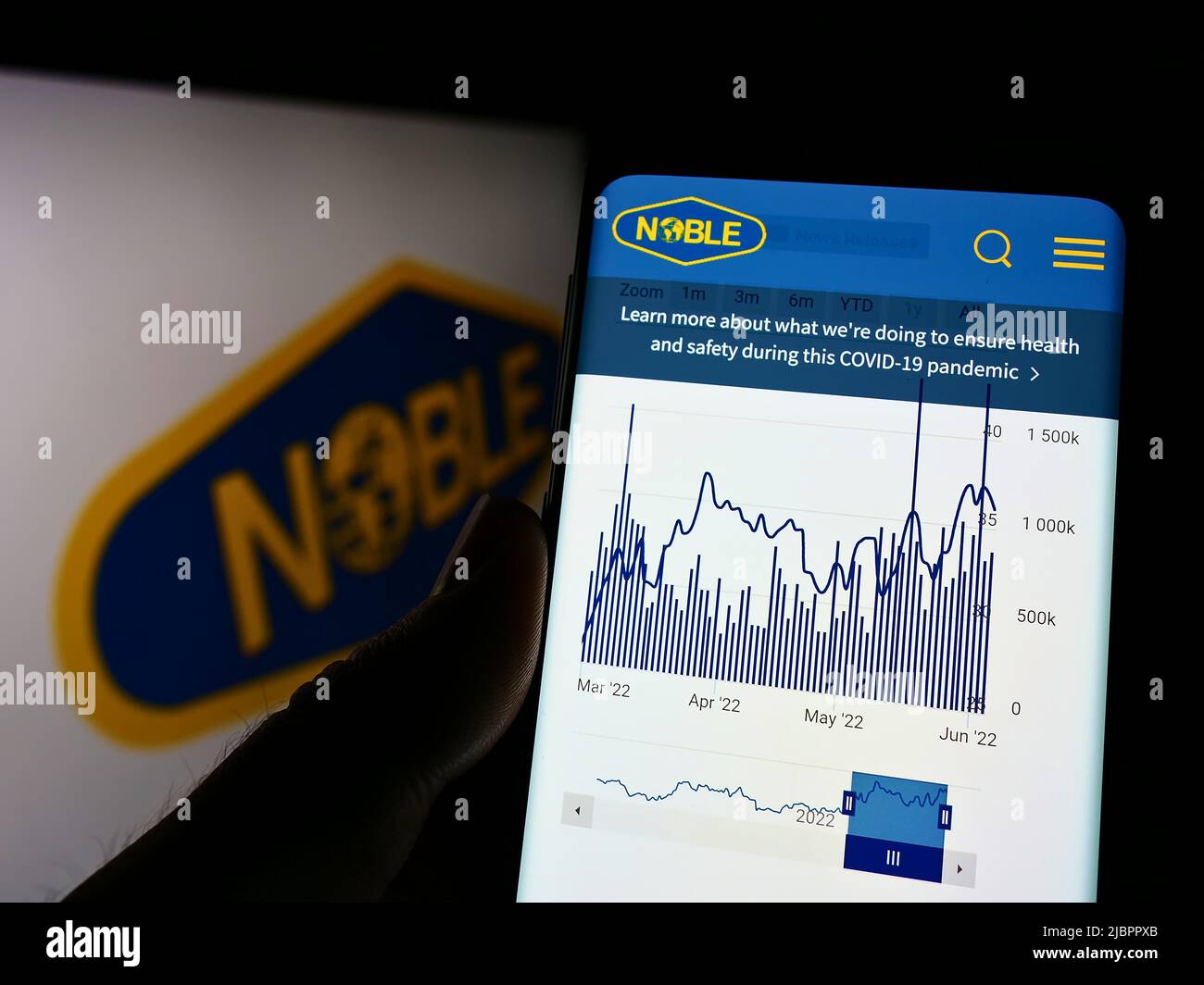 Person holding cellphone with webpage of drilling company Noble Corporation plc on screen in front of logo. Focus on center of phone display. Stock Photo