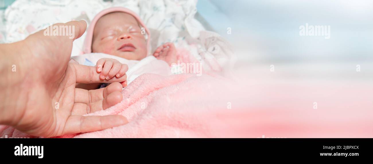 father hand holding their new born baby finger hand closeup ,newborn Sleeping in table in hospital Stock Photo