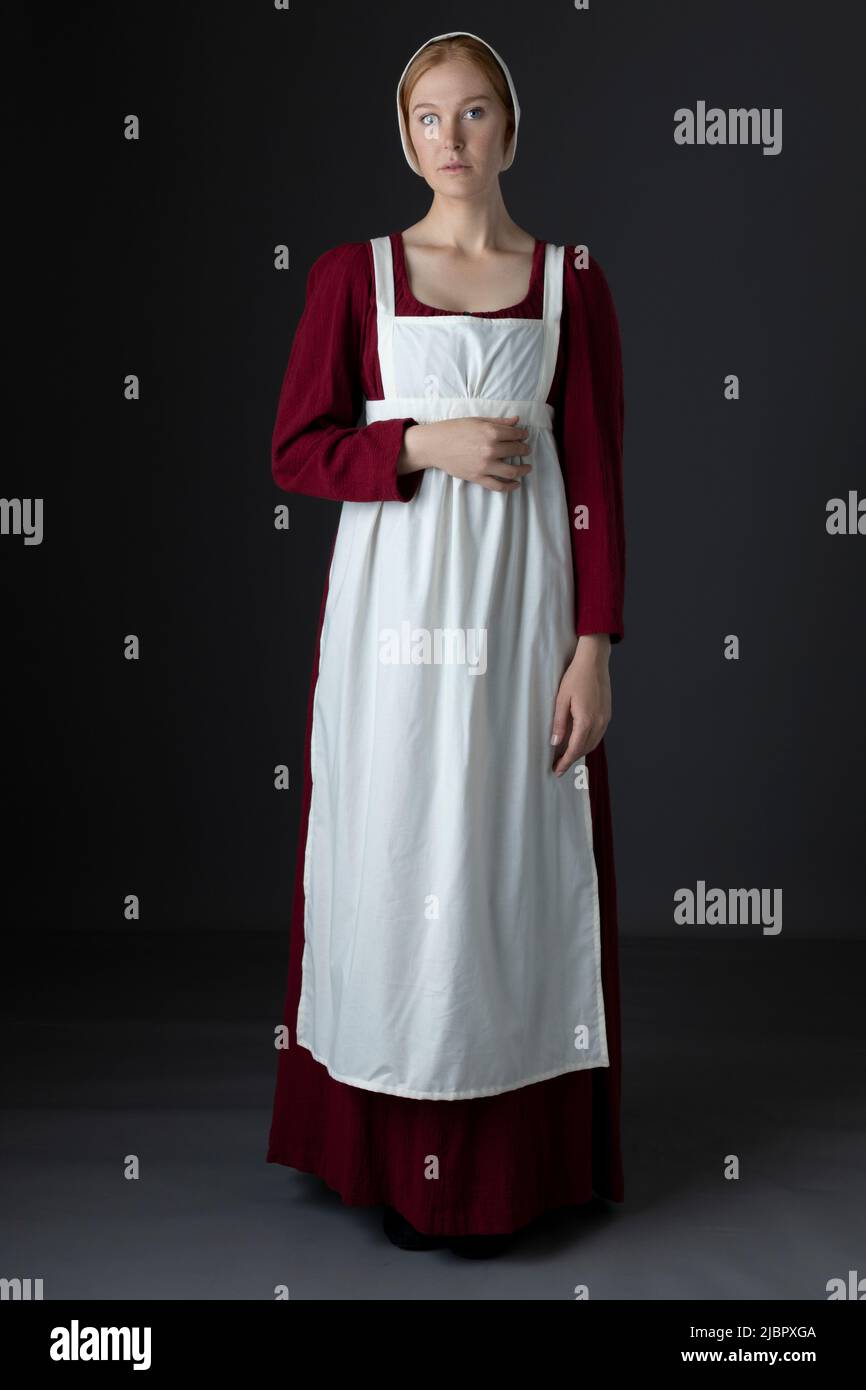 A Regency serving maid wearing a red dress and an apron Stock Photo