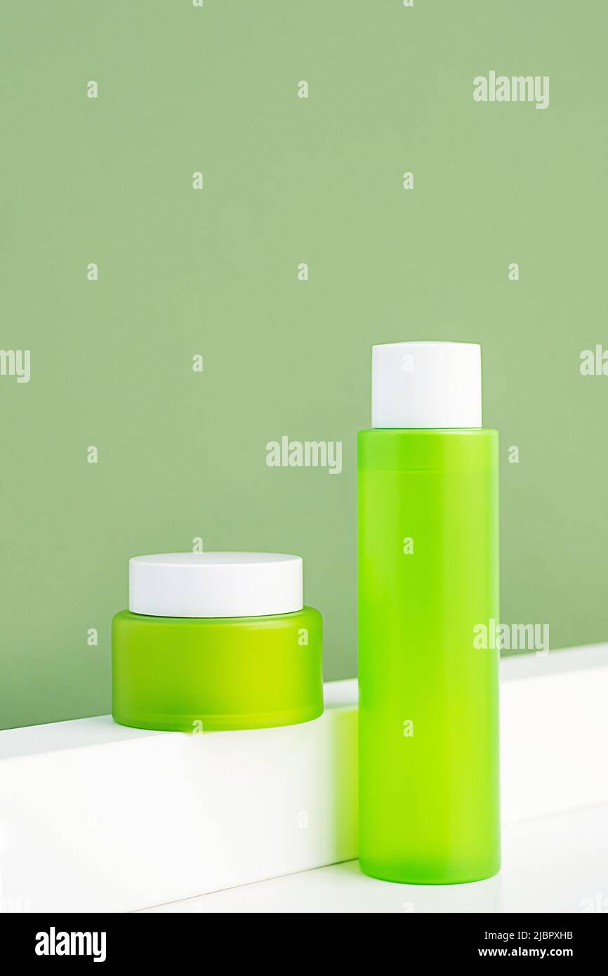 Mock up green cosmetic bottle and jar. Minimal monochrome composition of skin care products. Stock Photo