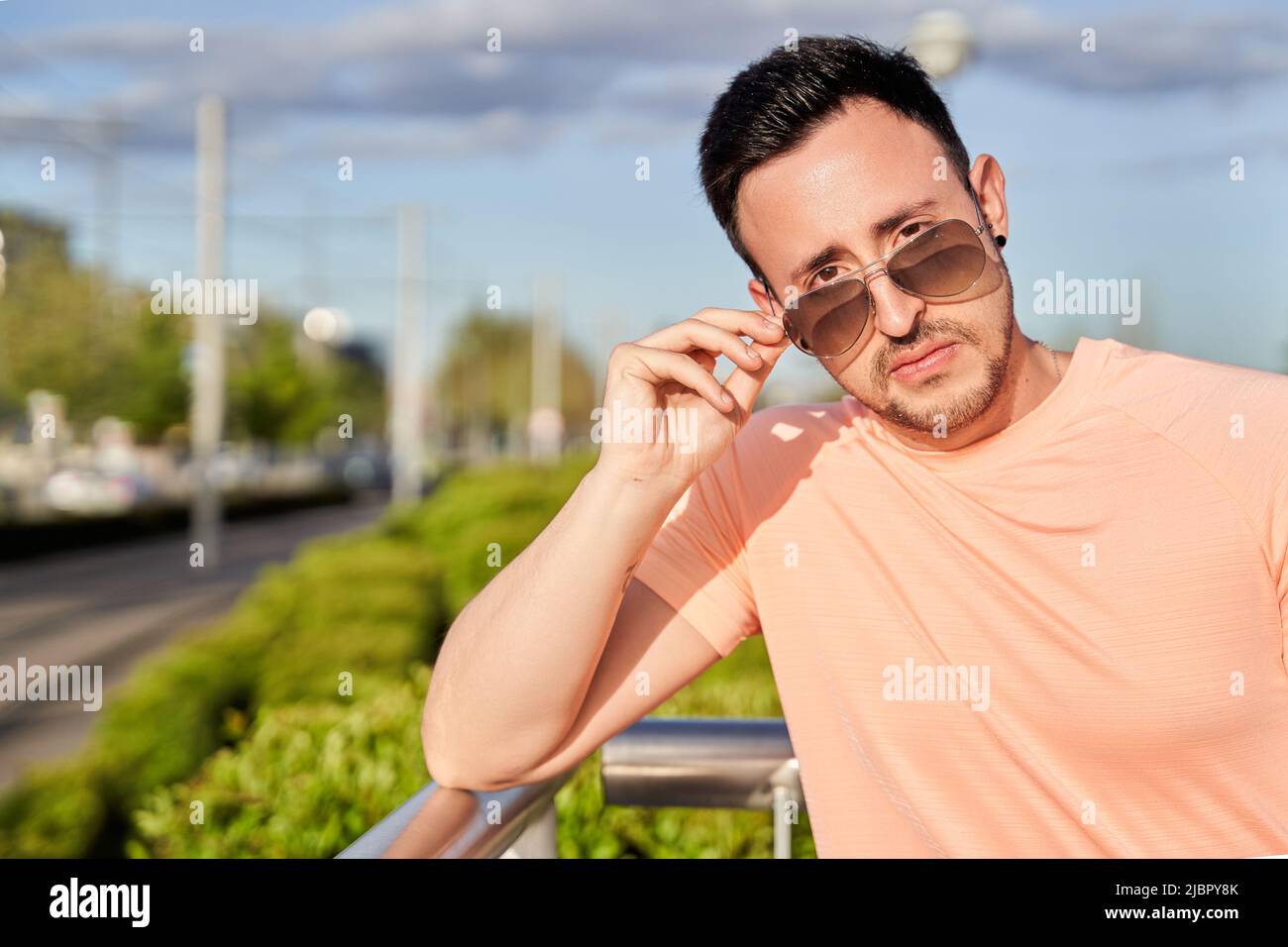 Serious young man looking at the camera over sunglasses on a sunny day on a city street. Stock Photo