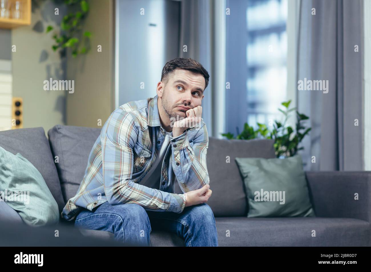 Sad man sitting on couch hi-res stock photography and images - Alamy