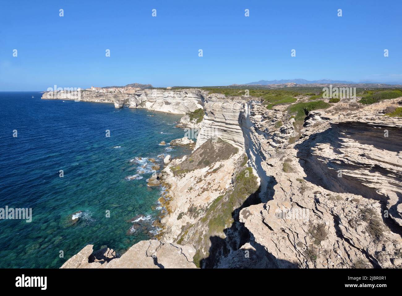Bonifacio coastline with limestone cliff overlooking the sea on clear blue sky Stock Photo