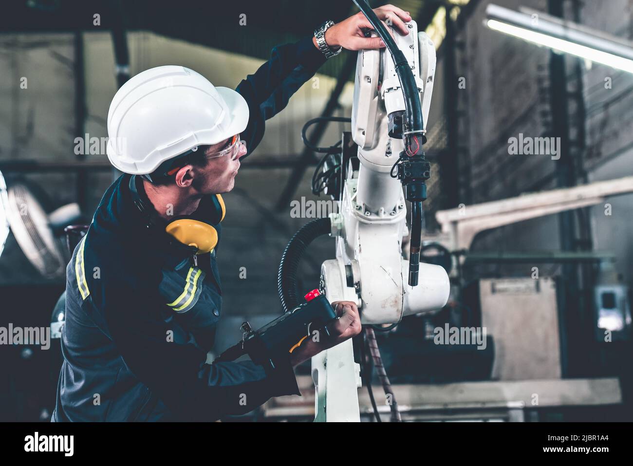 Young factory worker working with adept robotic arm in a workshop . Industry robot programming software for automated manufacturing technology . Stock Photo