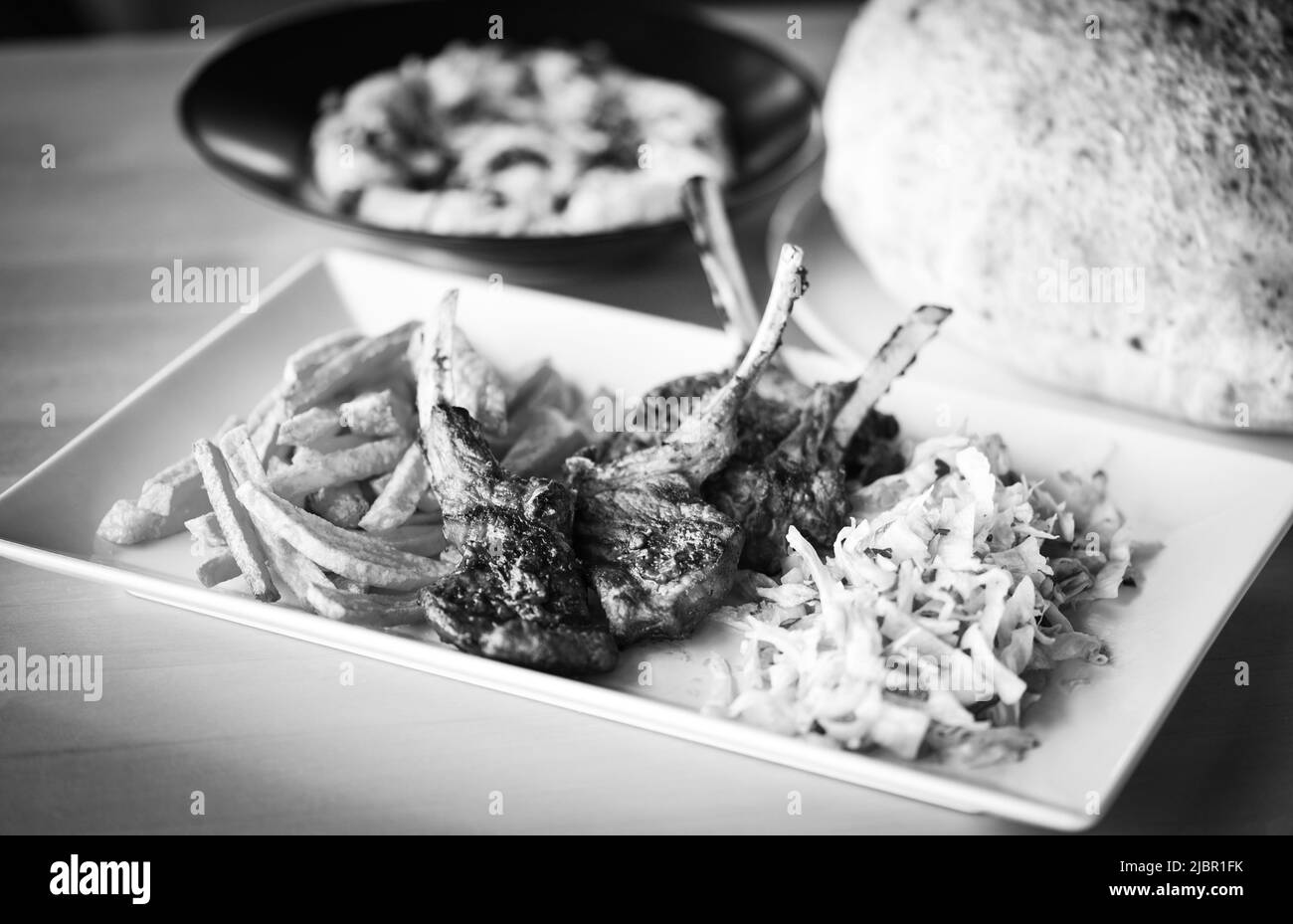 delicious grilled lamb chopsticks with french fries, pesto sauce & mix of lettuces Stock Photo