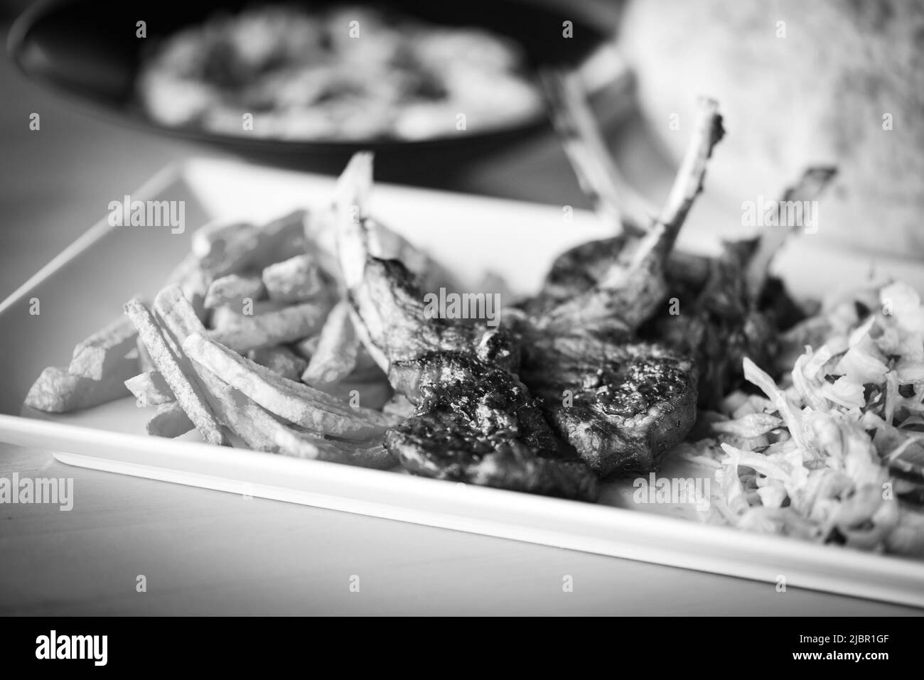 delicious grilled lamb chopsticks with french fries, pesto sauce & mix of lettuces Stock Photo