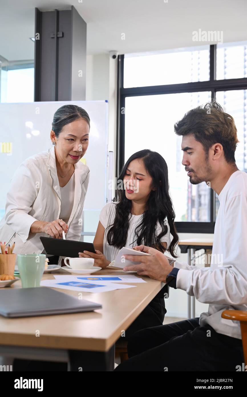 Senior older female executive ceo and young employee discuss corporate project together at briefing Stock Photo