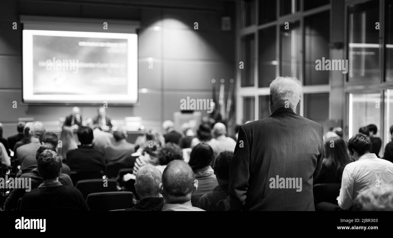 I have a question. Group of business people sitting in conference hall. Businessman raising his arm. Conference and Presentation. Business and Stock Photo