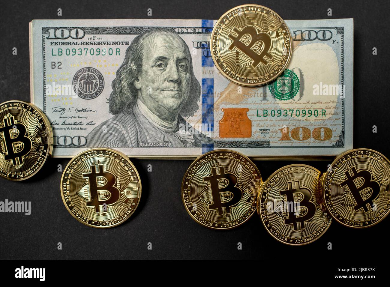 Gold Bitcoin coins on top of one hundred Dollar Banknotes. BTC Exchange to USD. United States of America Currency. Stock Photo