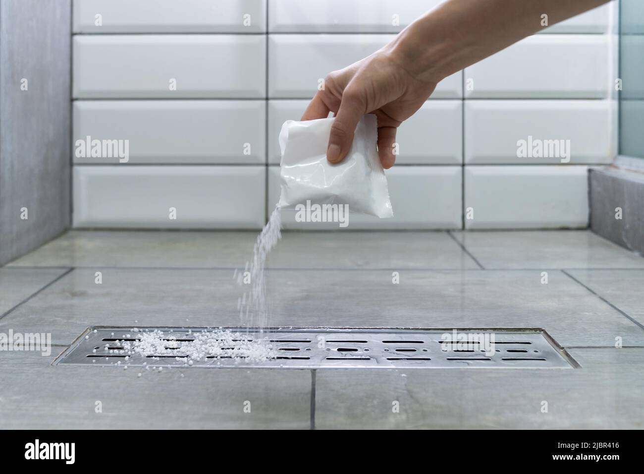 Closeup of female hand pouring pipe cleaner granules. Clean the blockages in bathroom with chemicals Stock Photo