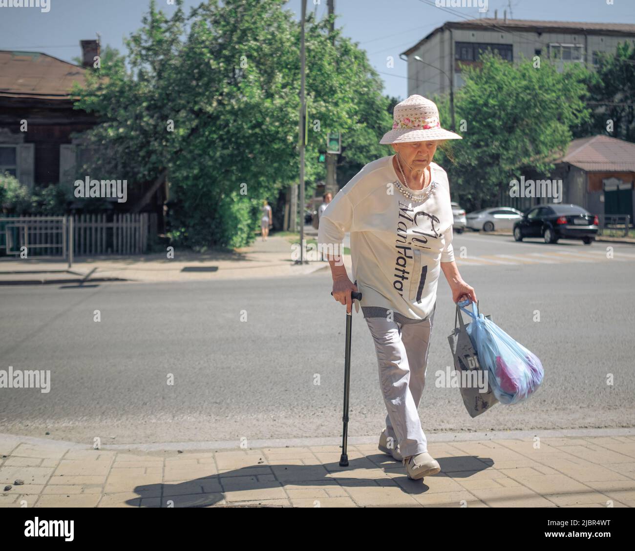 25 th of May, Russia, Tomsk, older woman with a hat walks on street editorial Stock Photo