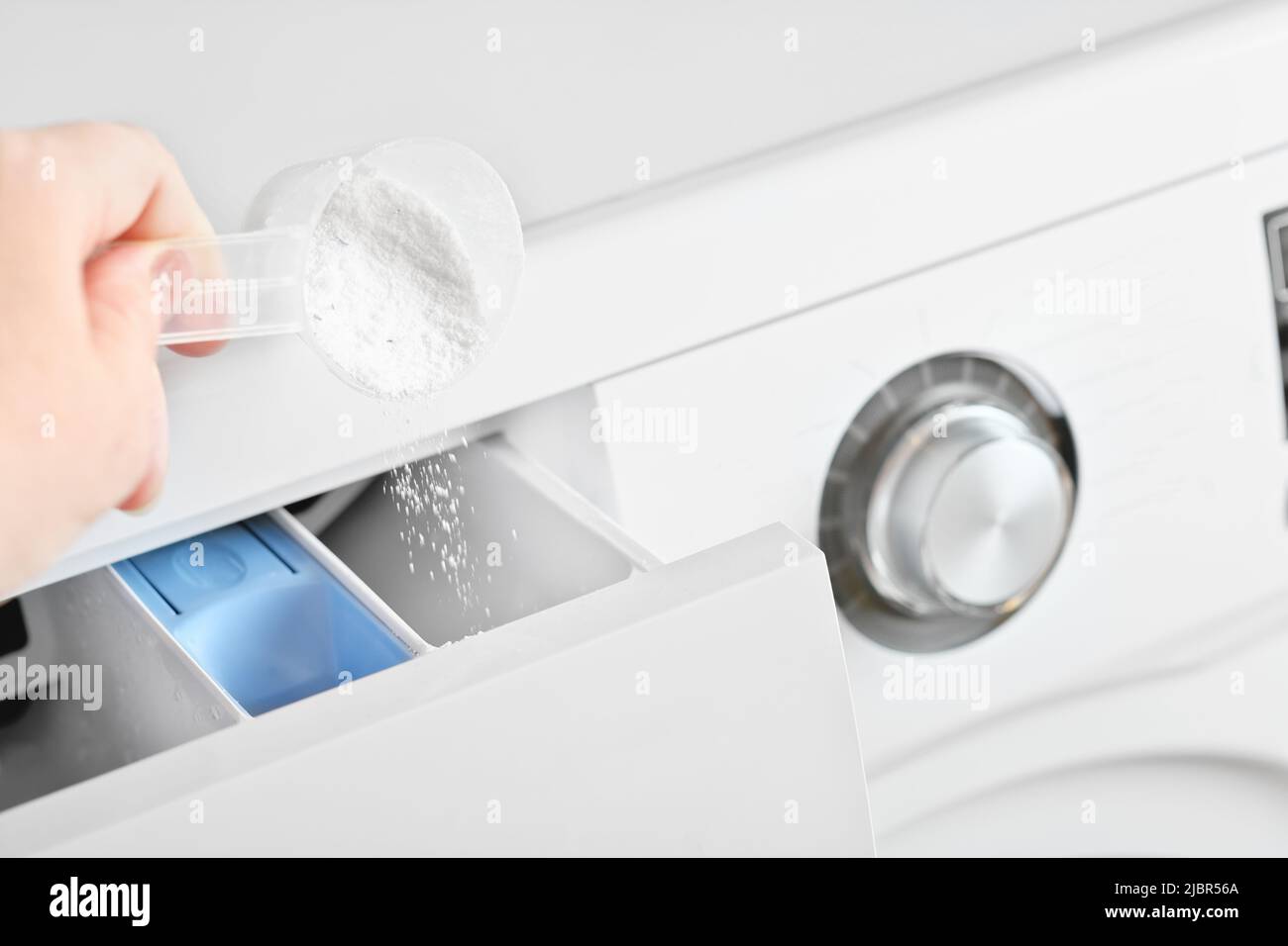 Woman pouring washing detergent into the washing machine tray. housekeeping and householding