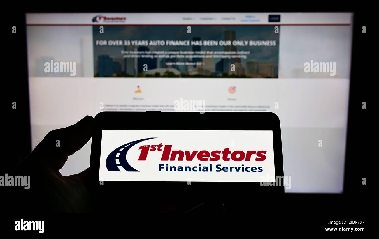 Person holding mobile phone with logo of First Investors Financial
