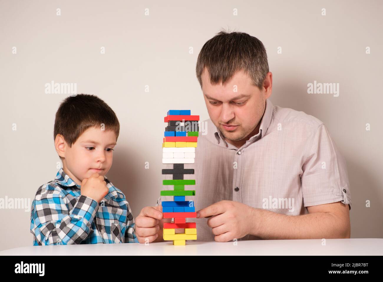 Dad and son play a board game together, pull parts out of the tower and try not to overwhelm the tower Stock Photo