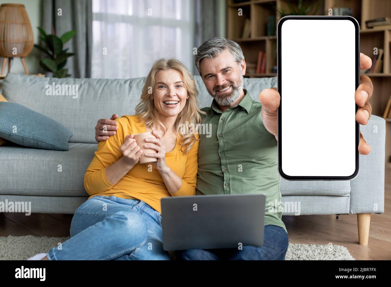 Great App. Middle Aged Spouses Demonstrating Blank Smartphone With White Screen Stock Photo