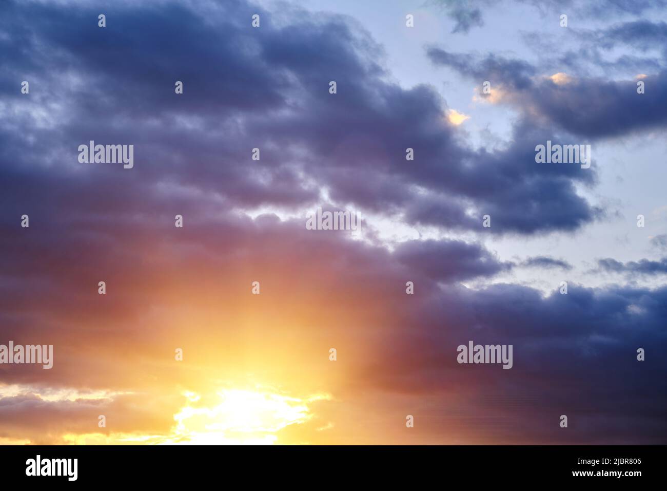 Thunderclouds with breaking rays sun at sunset Stock Photo