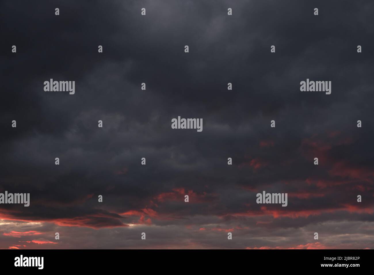 Thunderclouds with breaking rays sun at sunset Stock Photo