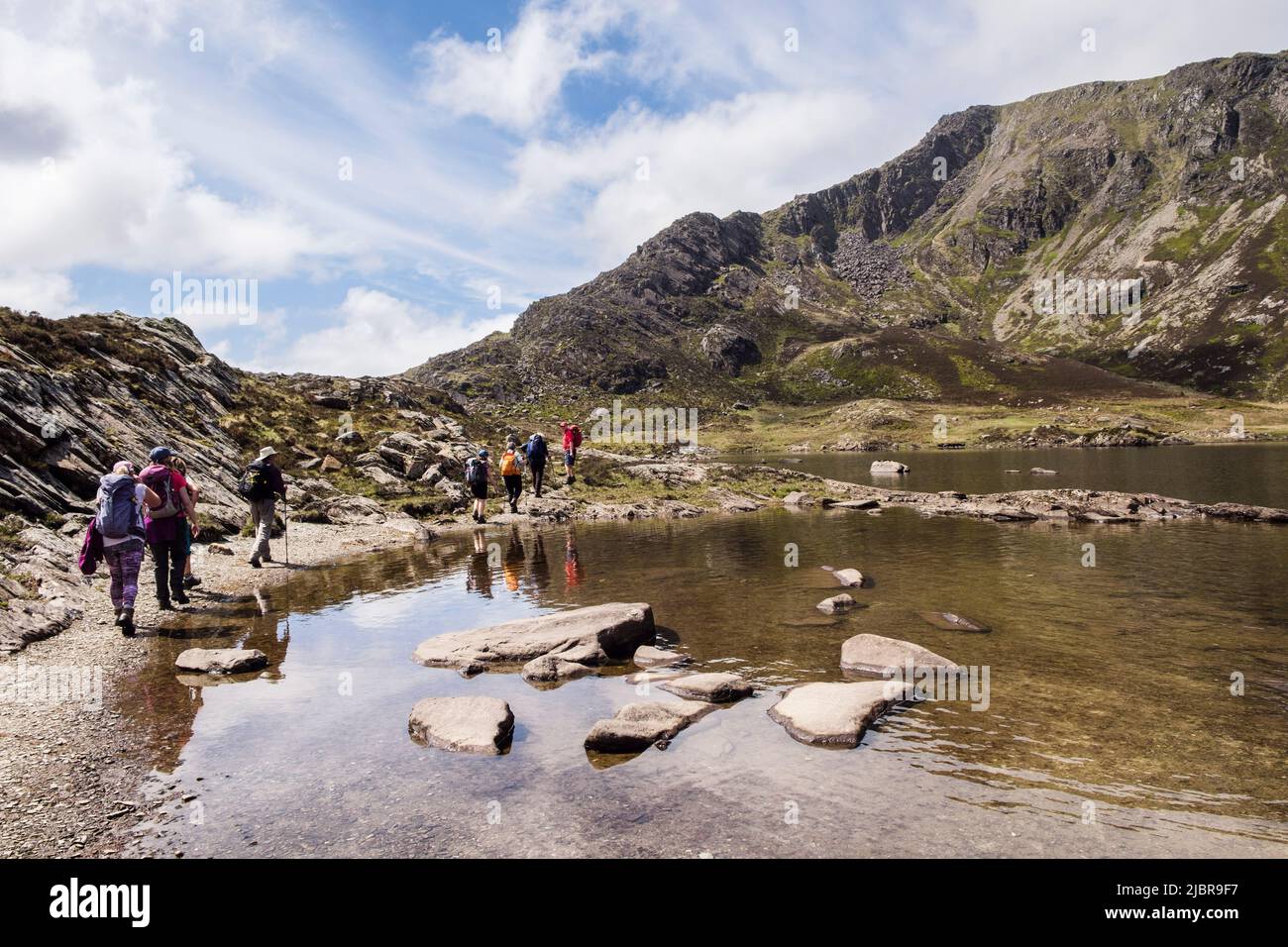 Hikers hiking around Llyn Y Foel lake in Cwm Y Foel below Moel Siabod Daear Ddu east ridge in Snowdonia National Park. Capel Curig, north Wales, UK Stock Photo