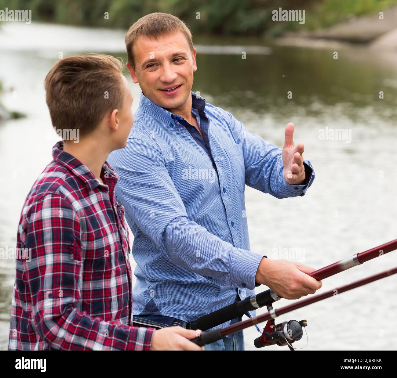 father and son fishing together on lake . Stock Photo