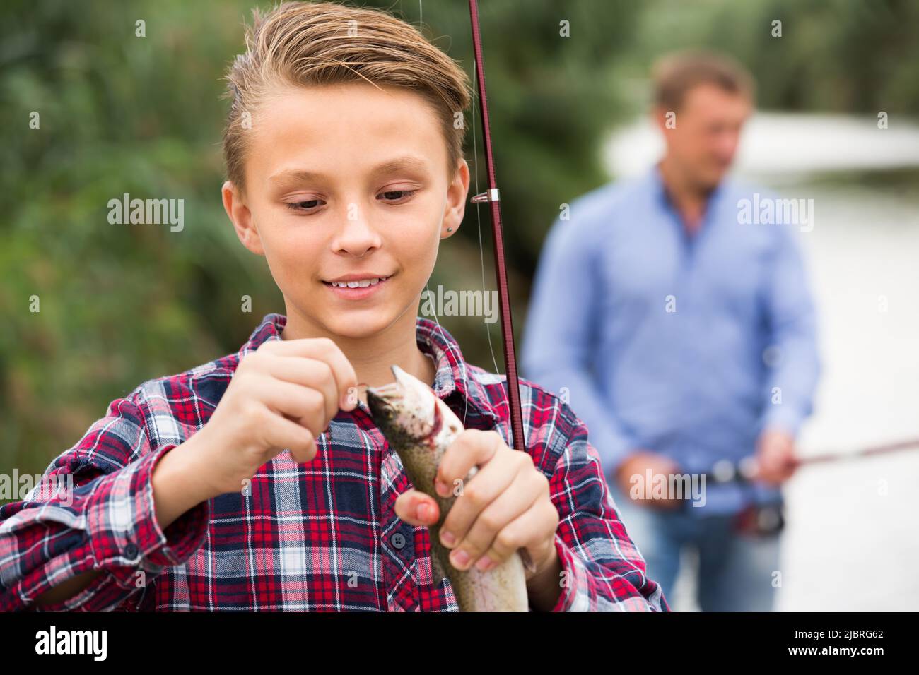 teenager boy holding catch fish on hook . Stock Photo