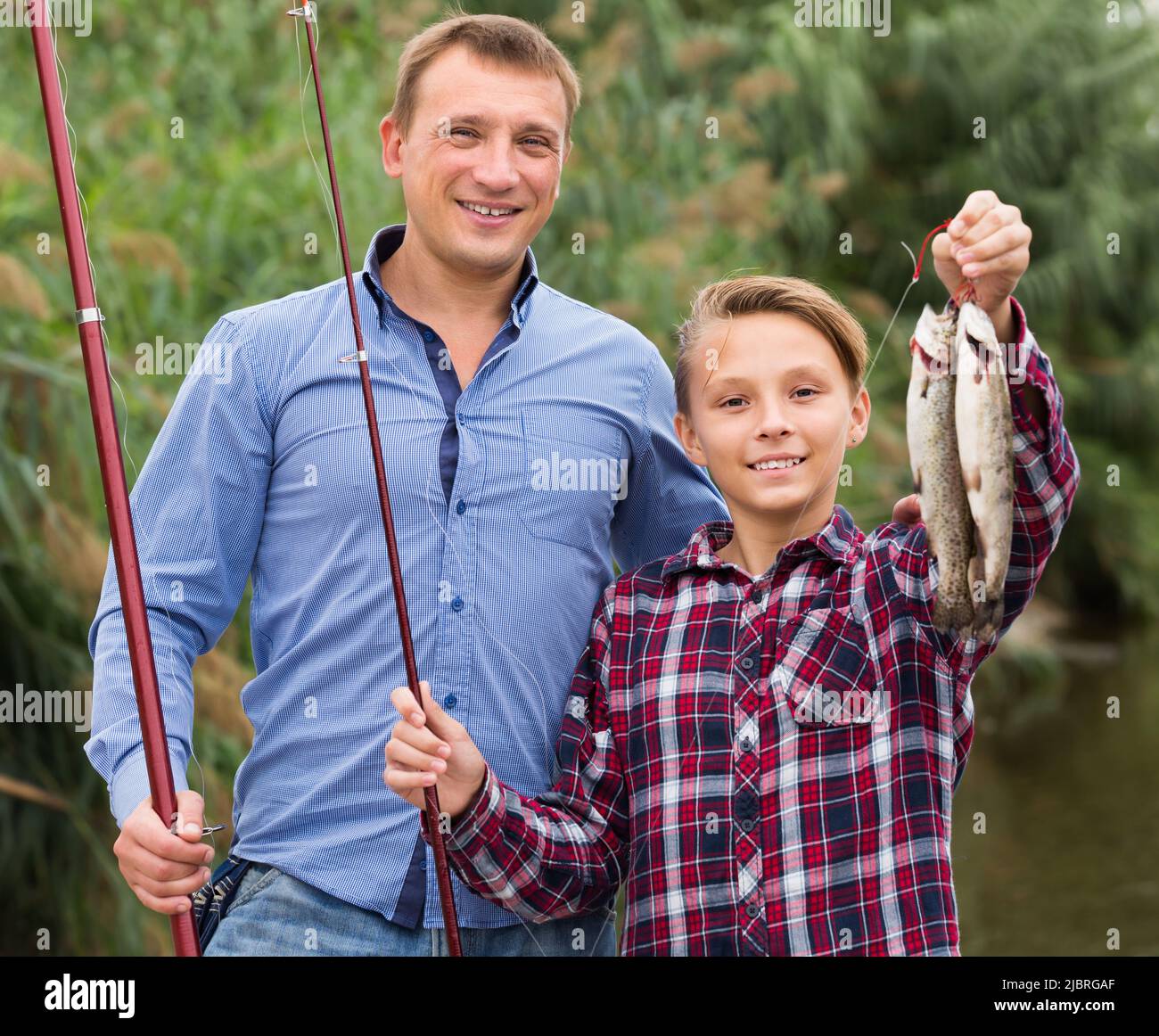 Glad father with son looking at fish on hook Stock Photo