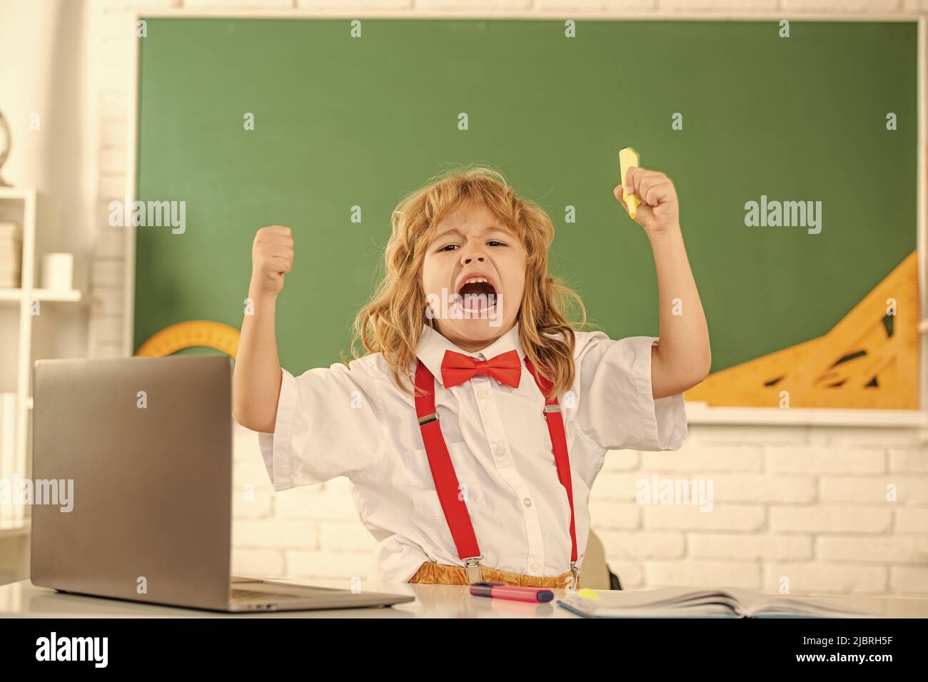 shouting kid boy in bow tie study in school classrrom at blackboard ...