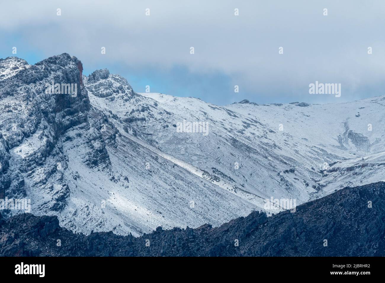 closeup of snowcapped mountain with clouds above the ridge use as abstract nature or background, concept Winter season and climate or weather Stock Photo