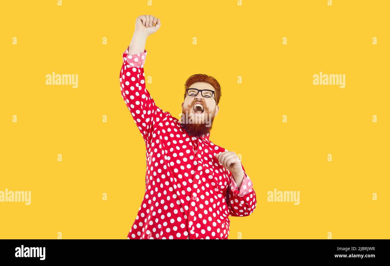 Funny happy crazy fat man standing on yellow background, raising his fist up and shouting YES Stock Photo
