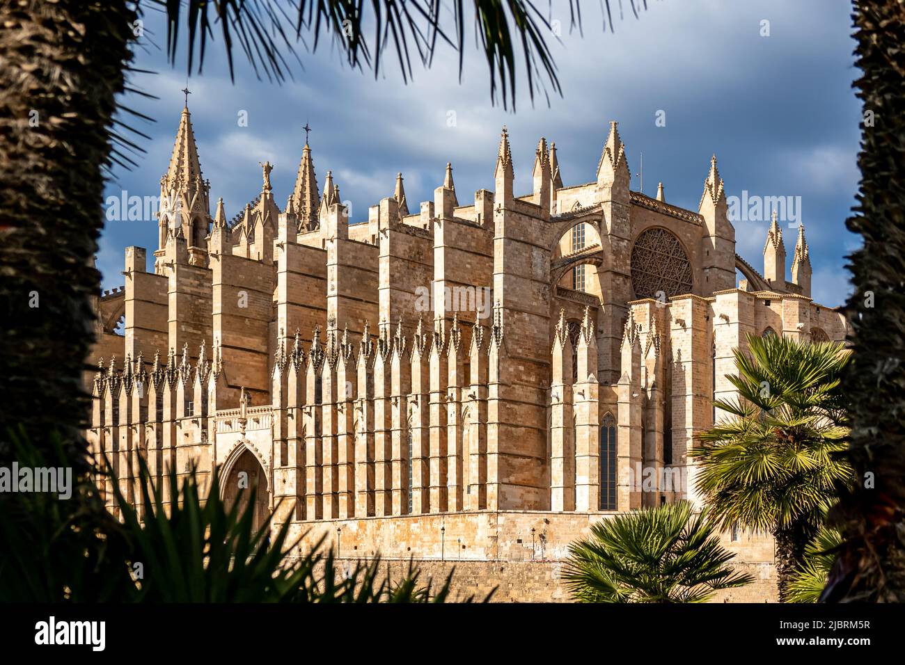 Photography of the gothic Cathedral of Santa Maria of Palma de Mallorca also called La Seu Cathedral in front of dark clouds and sunlit. Stock Photo