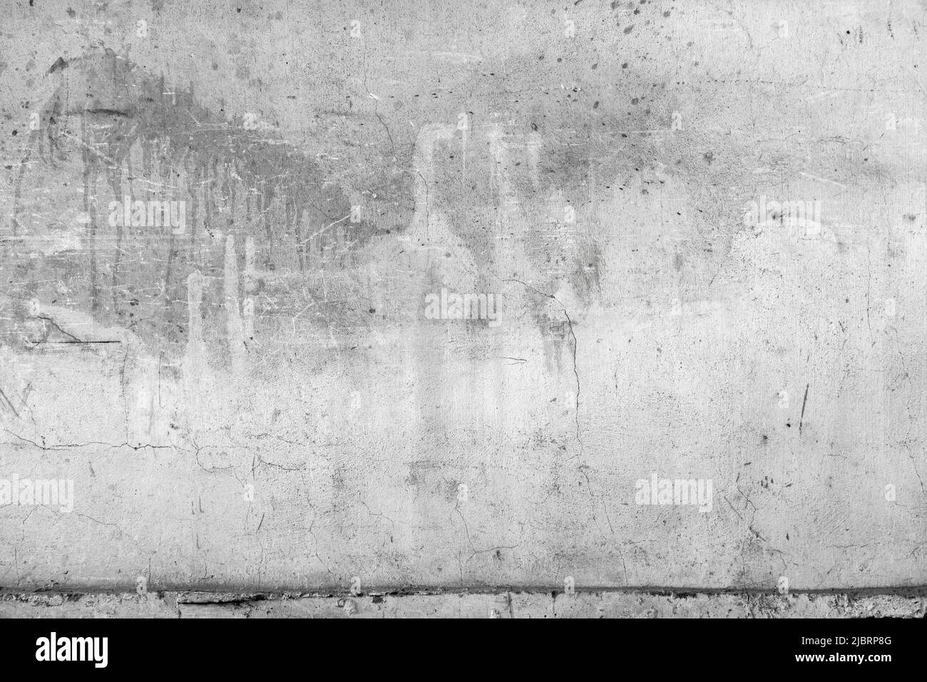 Old white concrete wall with cracks and paint spots, close up