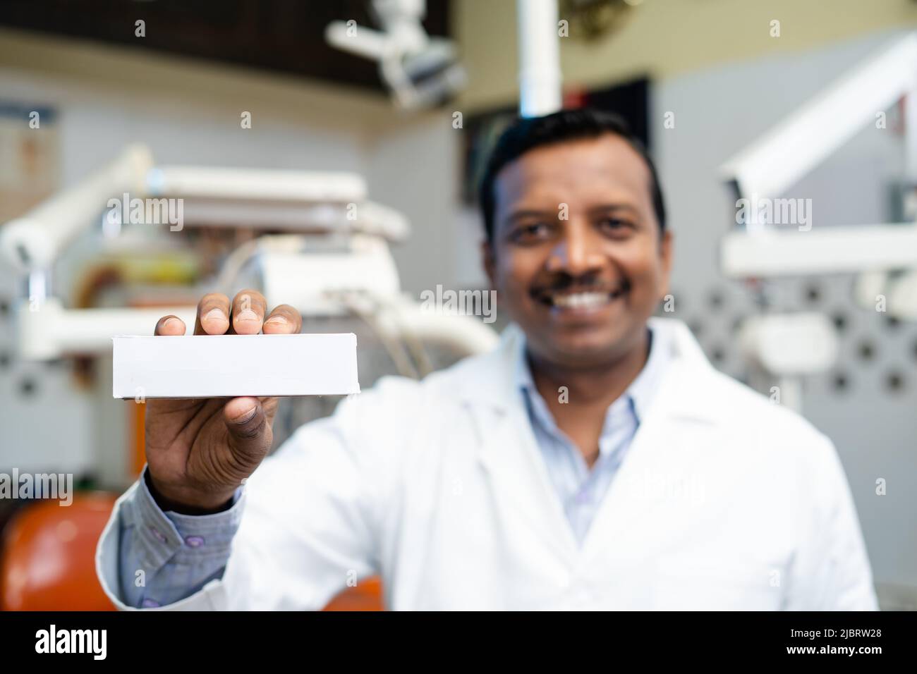 Happy smiling dentist showing toothpaste at hospital by looking at camera - concept of recommendation and approval of product Stock Photo