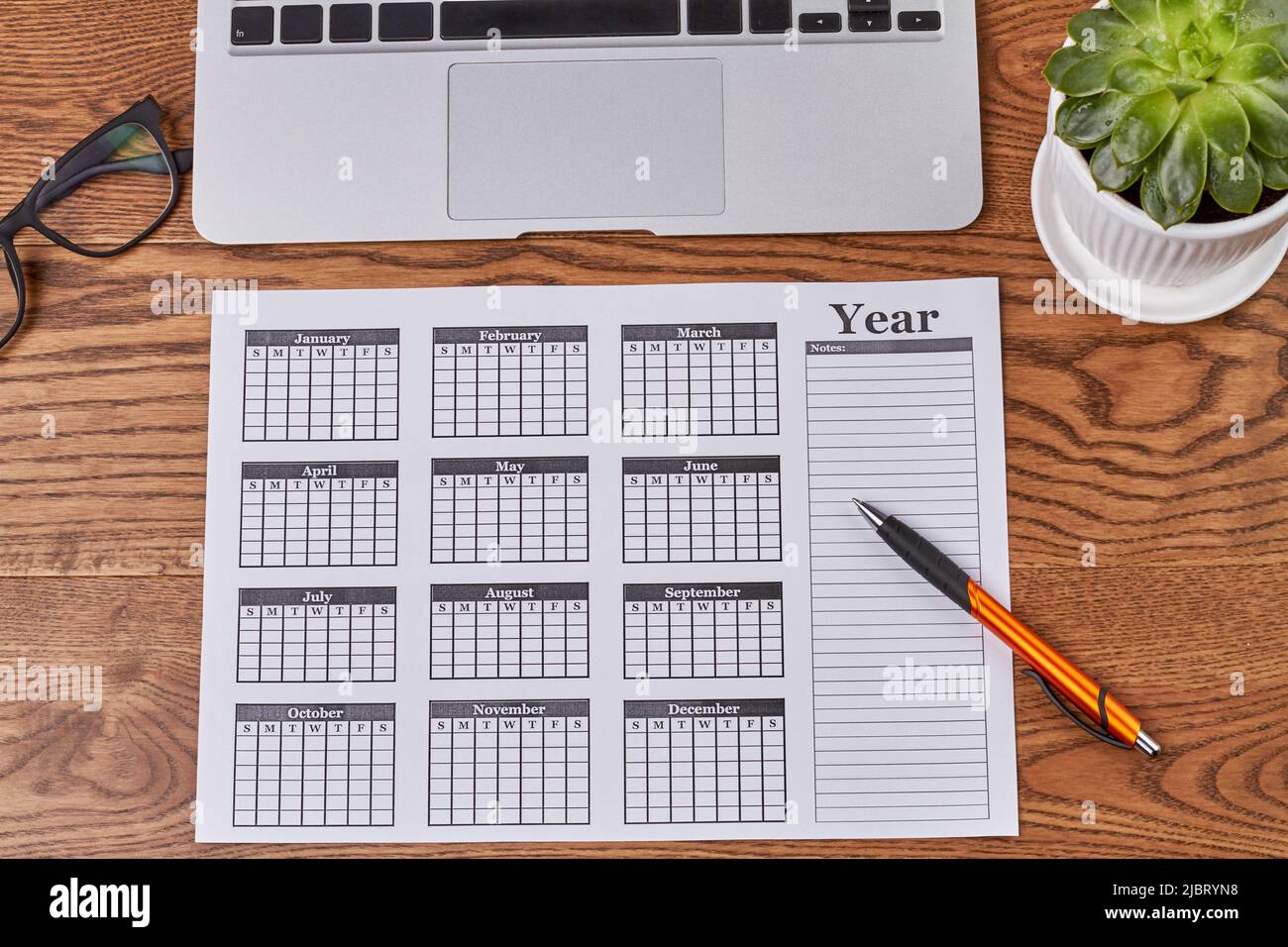Top view year calendar with pen and plant on wooden desk. Flat lay ...