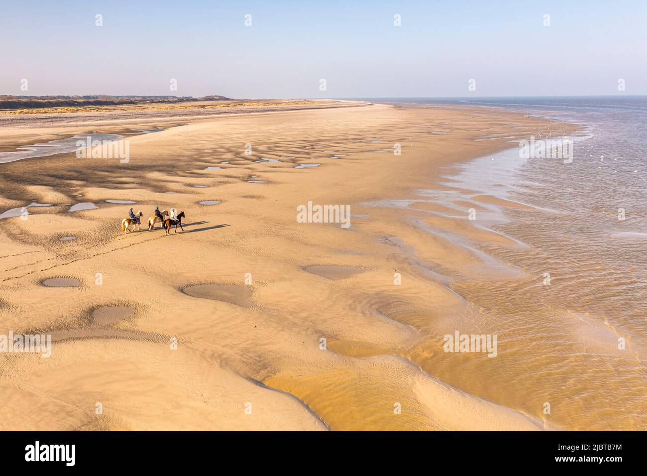 France, Somme, Le Hourdel, three riders walking with their horses on the huge sandbanks uncovered by the tide (aerial view) Stock Photo