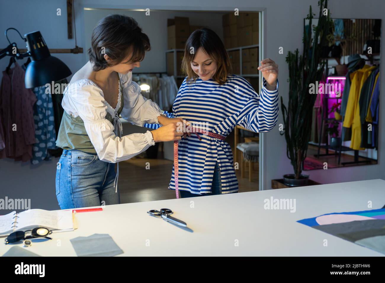 Fashion designer woman takes measurements with measuring tape of client ...