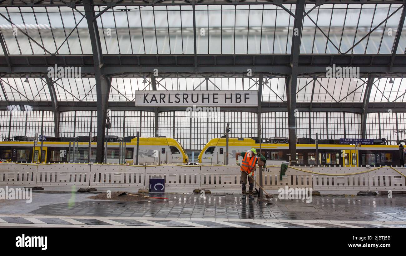 Karlsruhe, Germany - Aug 28, 2021: Interior of Karlsruhe main station with sign 'Karlsruhe HBF'. With construction worker and train. Stock Photo