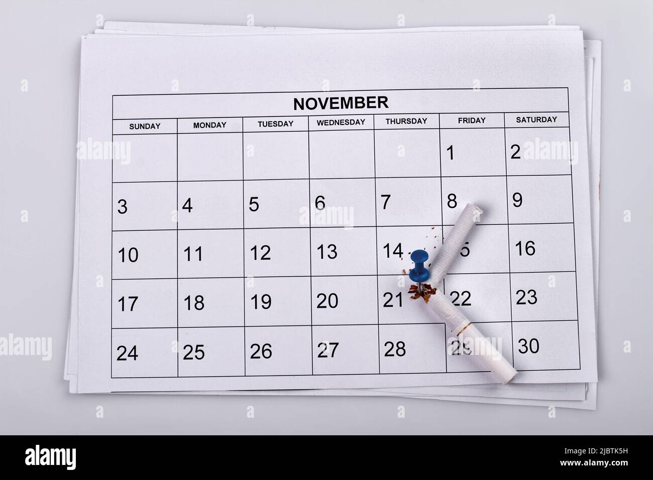 Broken cigarette with push pin on the month calendar. November calendar on white background. Stock Photo