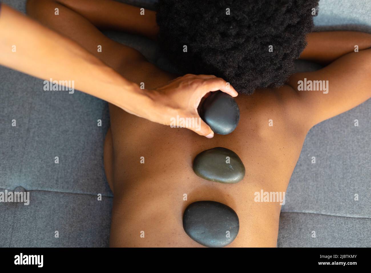 African american woman woman receiving hot stone massage at home Stock Photo