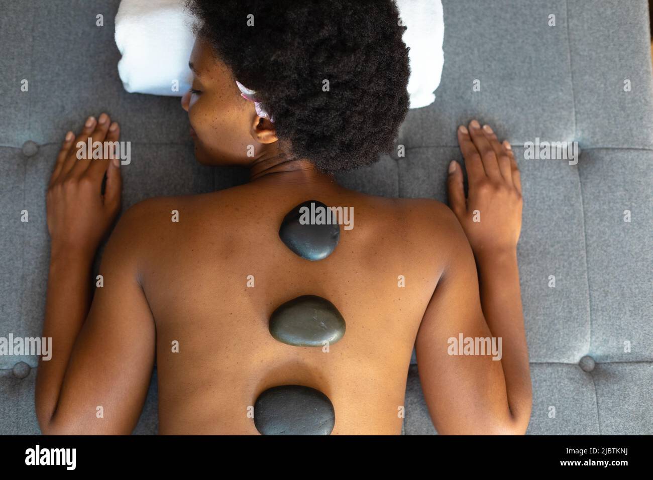 African american woman woman with eyes closed receiving hot stone massage at home Stock Photo