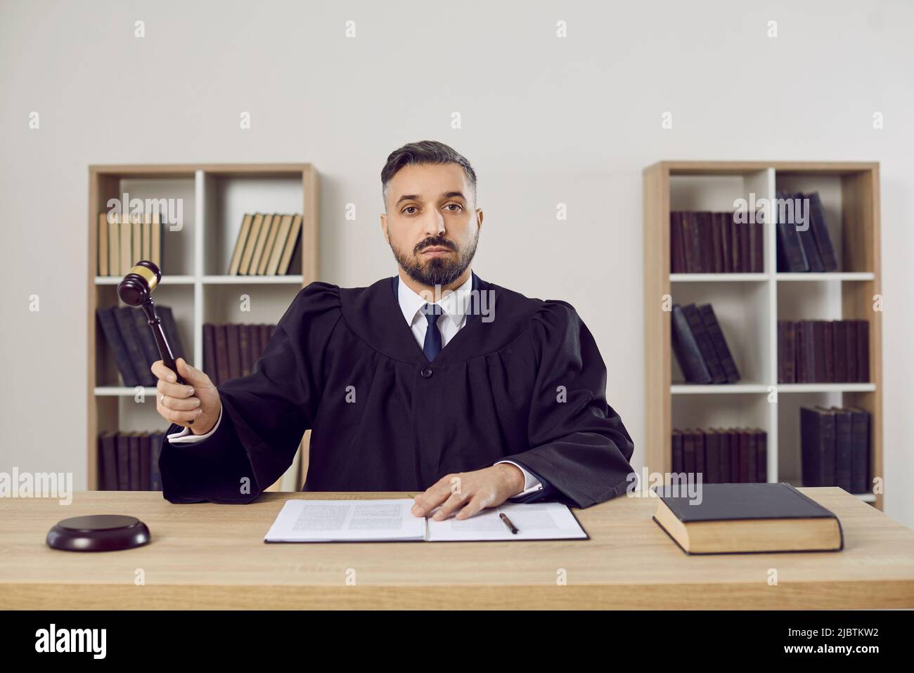 Ethnic male judge in robe strike hammer Stock Photo