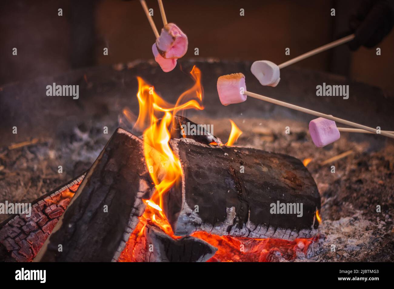 Toasting a marshmallow over an open flame at Christmas market Hyde Park Winter Wonderland in London Stock Photo