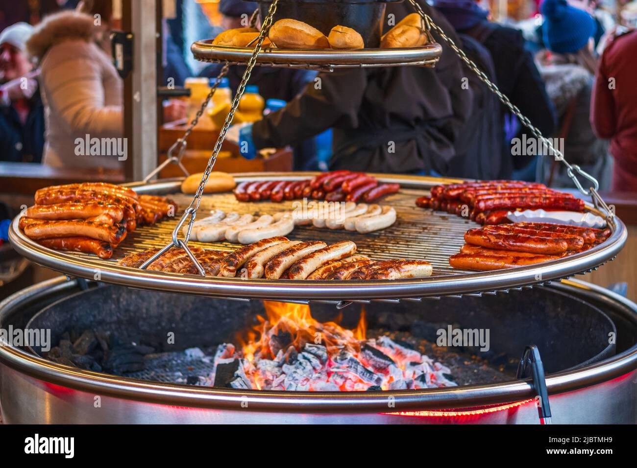 Grilling sausages on barbecue grill at a food stall of Christmas market Hyde Park Winter Wonderland in London Stock Photo