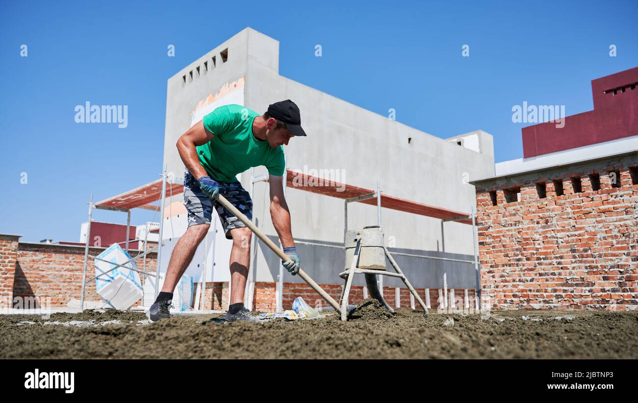 Full length of male worker shoveling sand-cement mix while working 