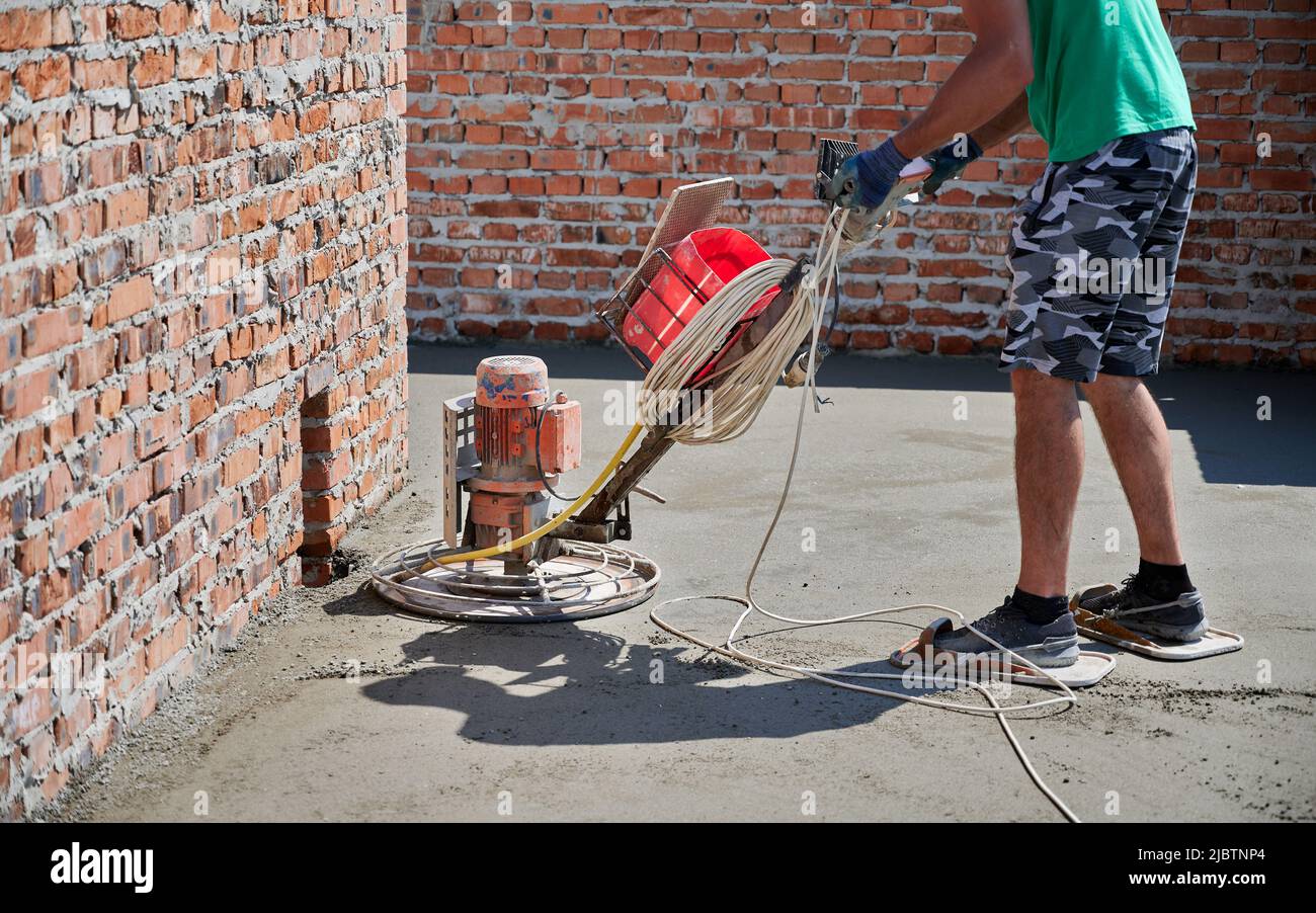 Close up of man builder using troweling machine while screeding floor