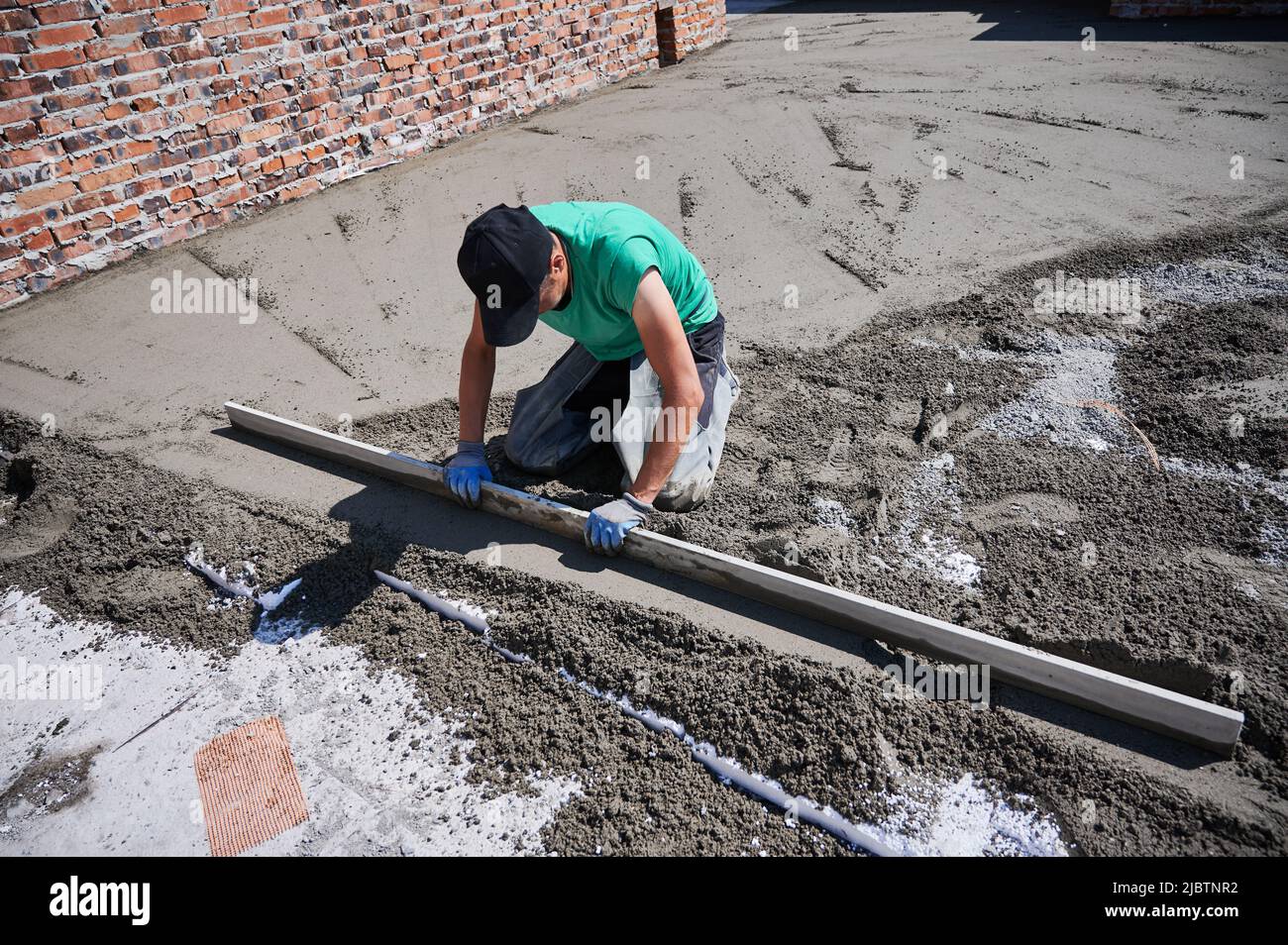 Man contractor placing screed rail on the floor covered with sand