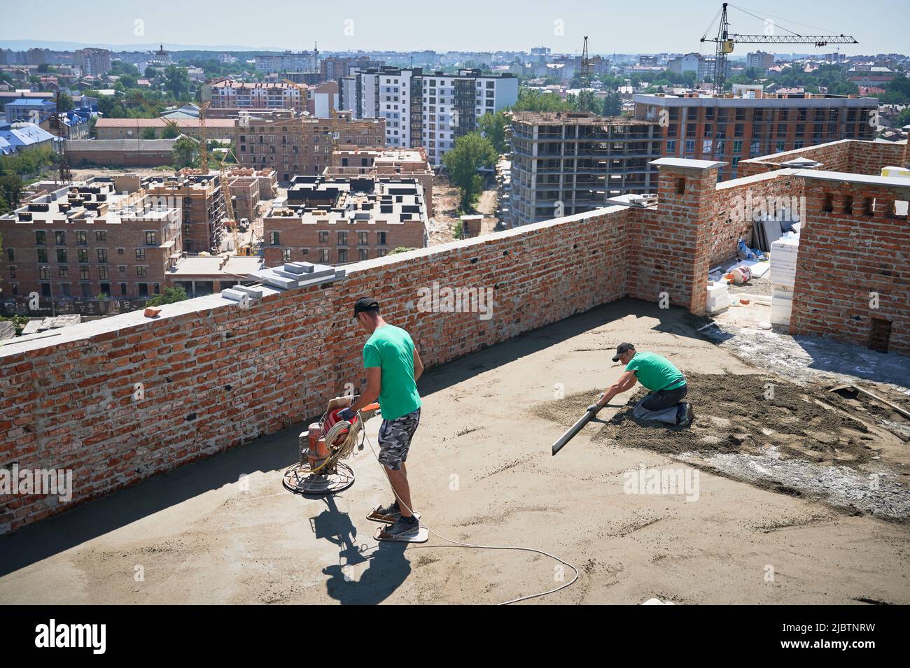 Man builder using troweling machine while screeding floor on the roof
