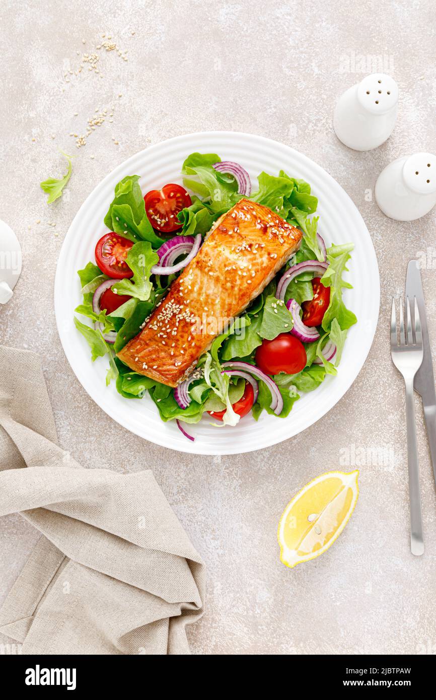 Grilled salmon fish fillet and fresh vegetable salad with tomato, red onion and lettuce Stock