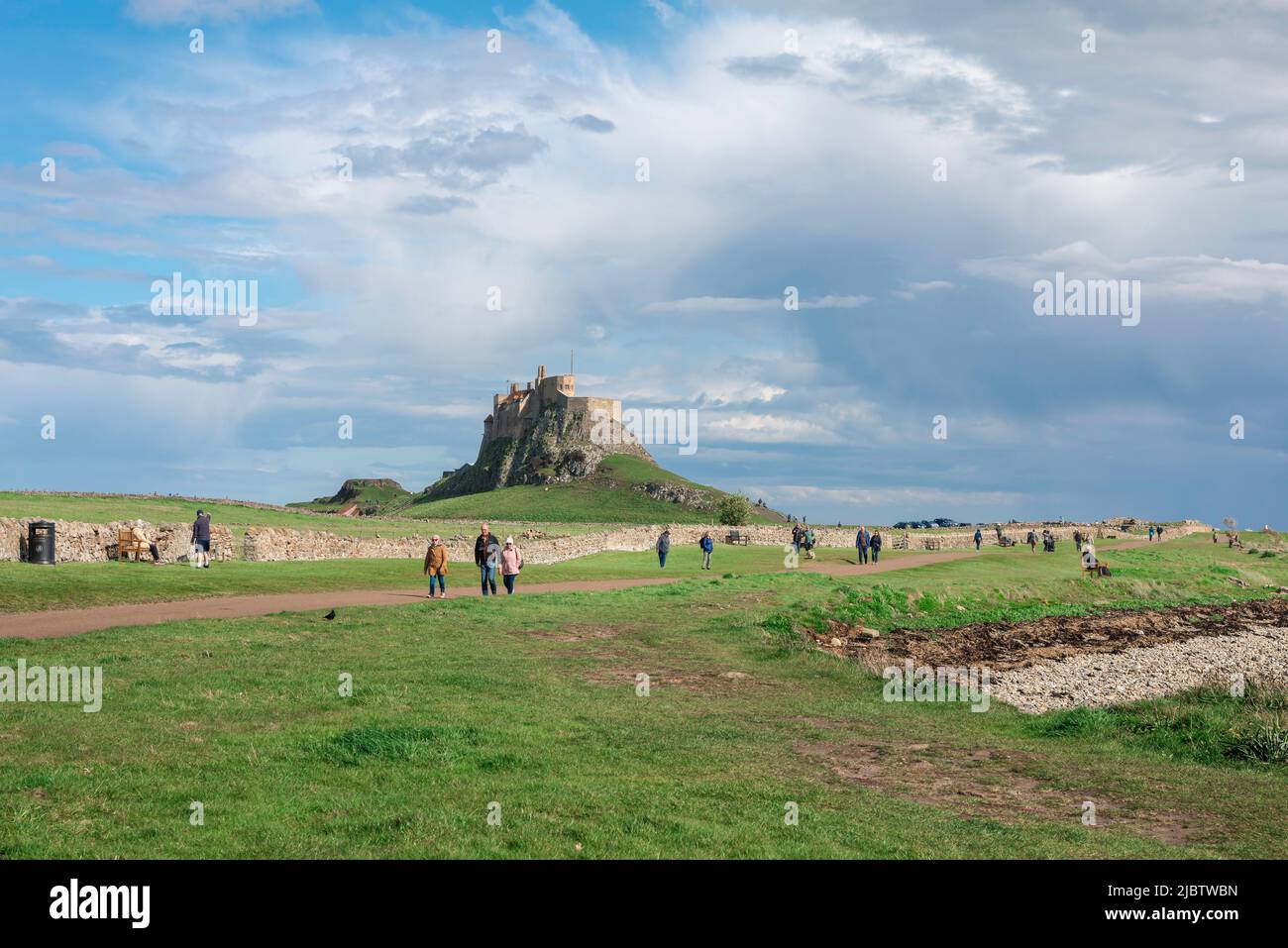 Holy Island Castle, view of the 16th century castle sited on Holy Island (Lindisfarne) with people walking near the foreshore, Northumberland, UK Stock Photo